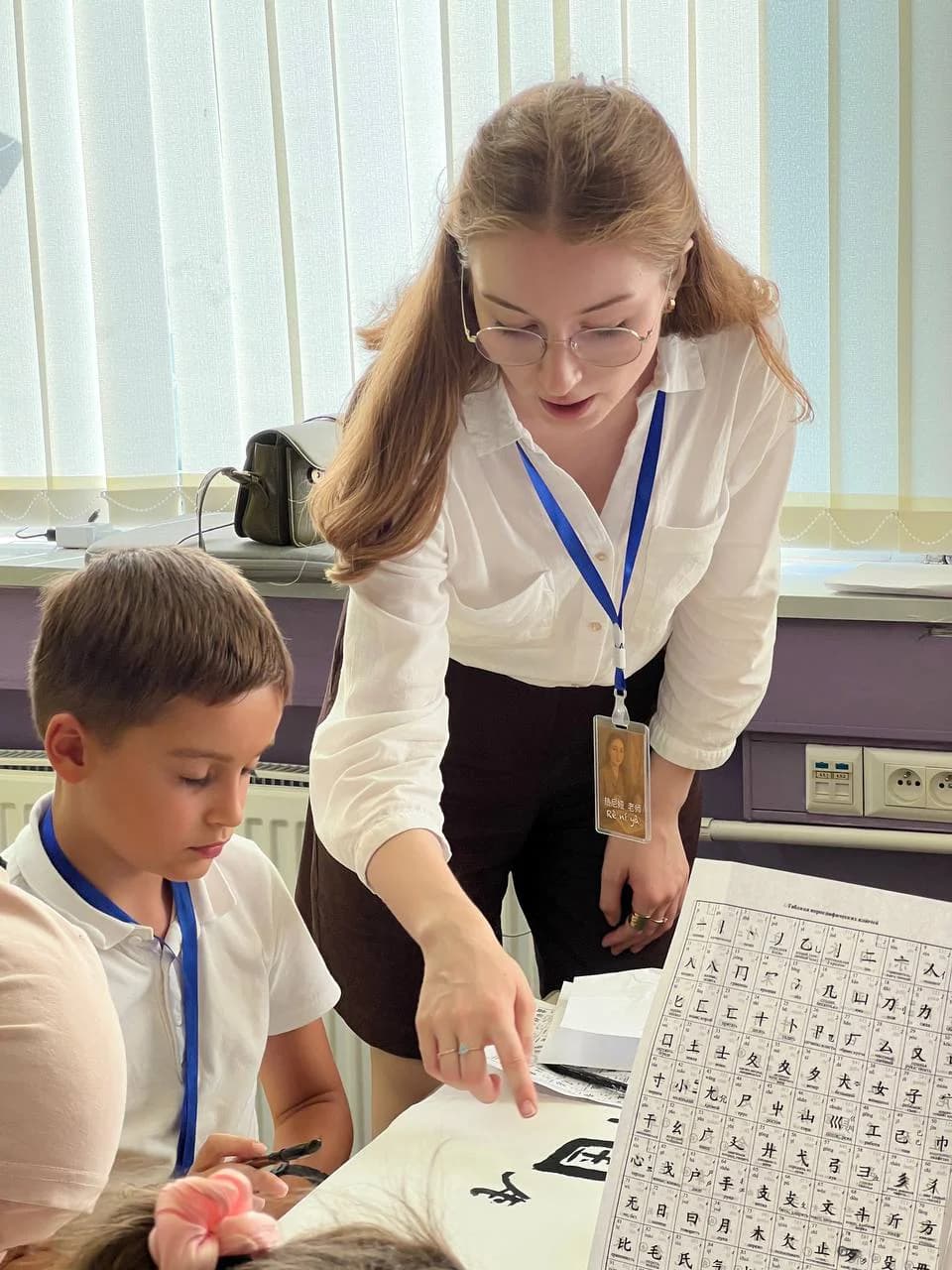 Преподаватель объясняет ученику написание иероглифов на уроке китайского языка.